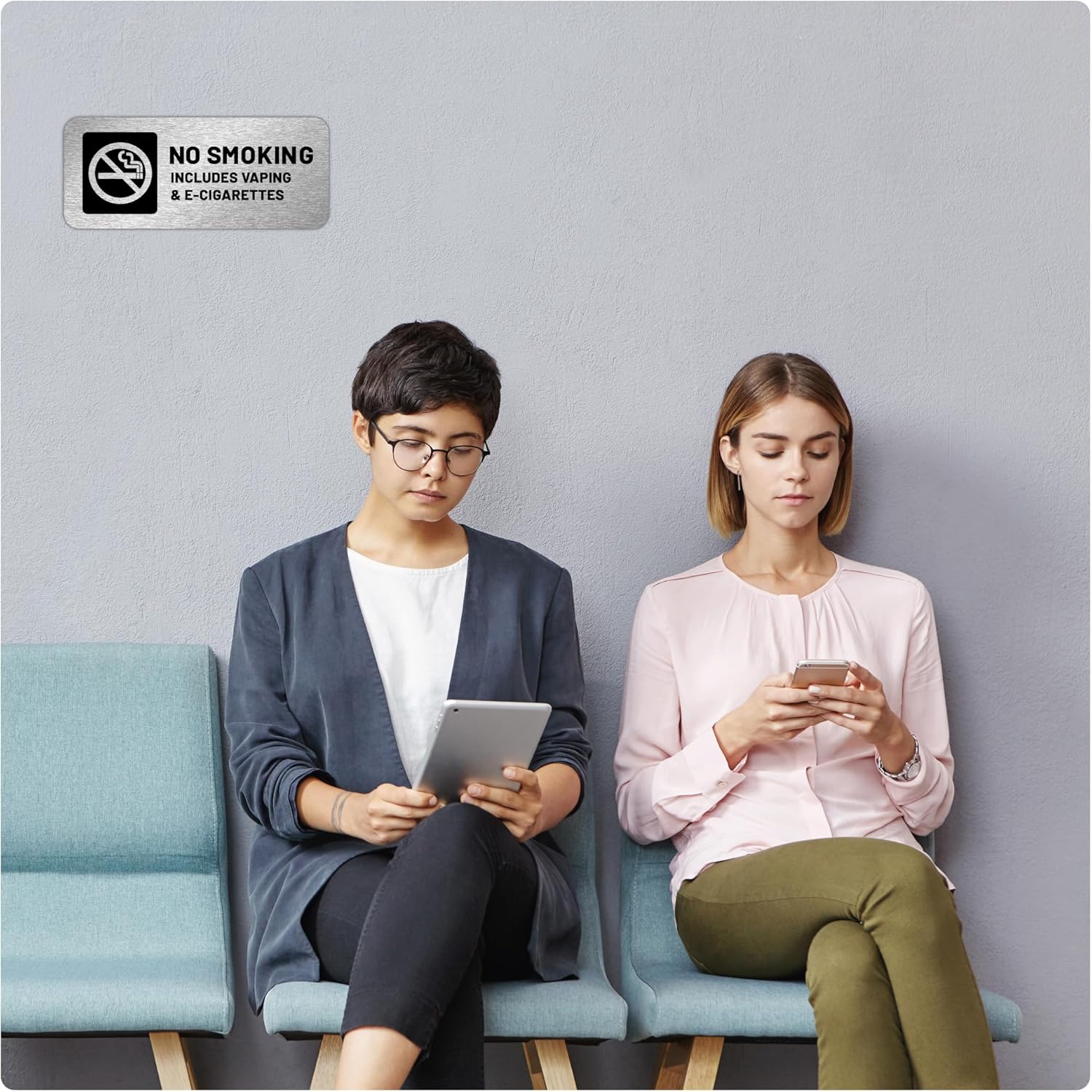 A silver aluminum no smoking sign with prohibition symbol and text indicating no smoking or vaping includes vaping and e-cigarettes.